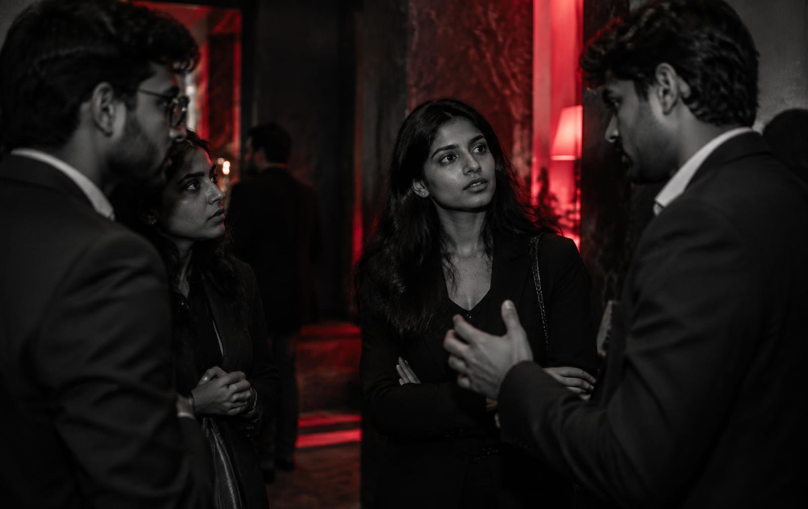 Attendees in conversation in a red-lit foyer